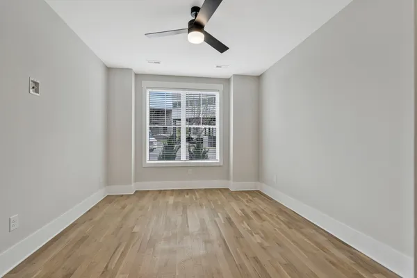 a view of an empty room with wooden floor and a window