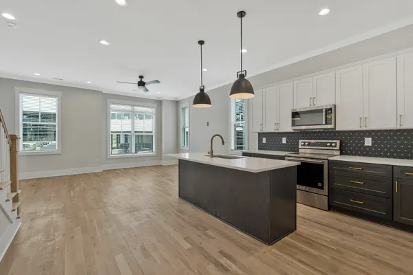 a large kitchen with stainless steel appliances granite countertop a stove a sink dishwasher a microwave oven and a wooden cabinets