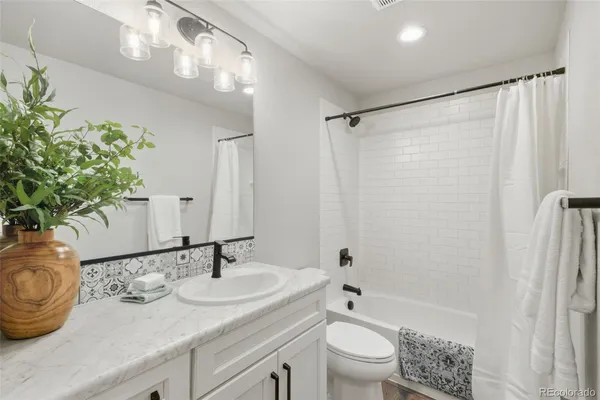 a bathroom with a granite countertop sink a toilet and shower