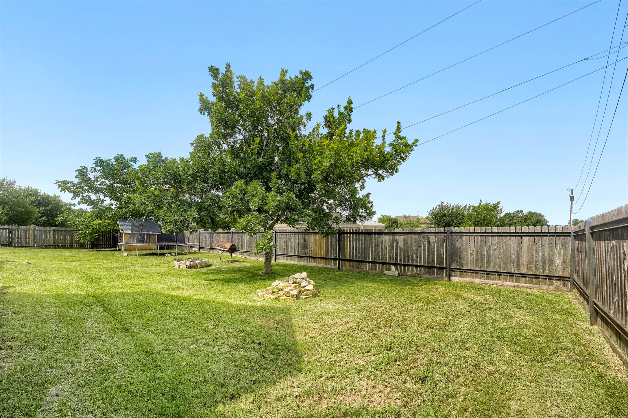1105 2nd Street Jarrell, TX 76537 - Photo 25 of 27 A spacious backyard with mature trees and a sturdy privacy fence defines this inviting outdoor space.