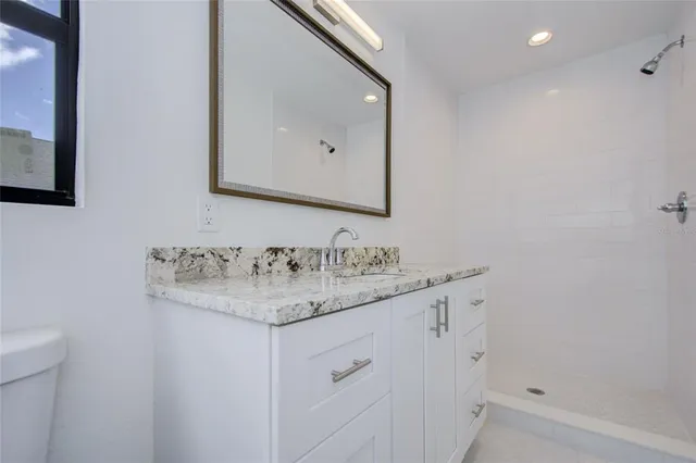 a bathroom with a granite countertop toilet sink and mirror