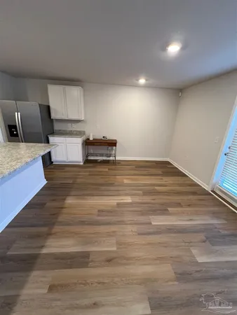 a view of kitchen and empty room with wooden floor