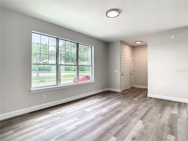 an empty room with wooden floor and windows