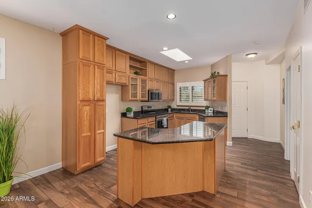 a kitchen with stainless steel appliances granite countertop a sink a refrigerator and a granite counter tops with wooden floors