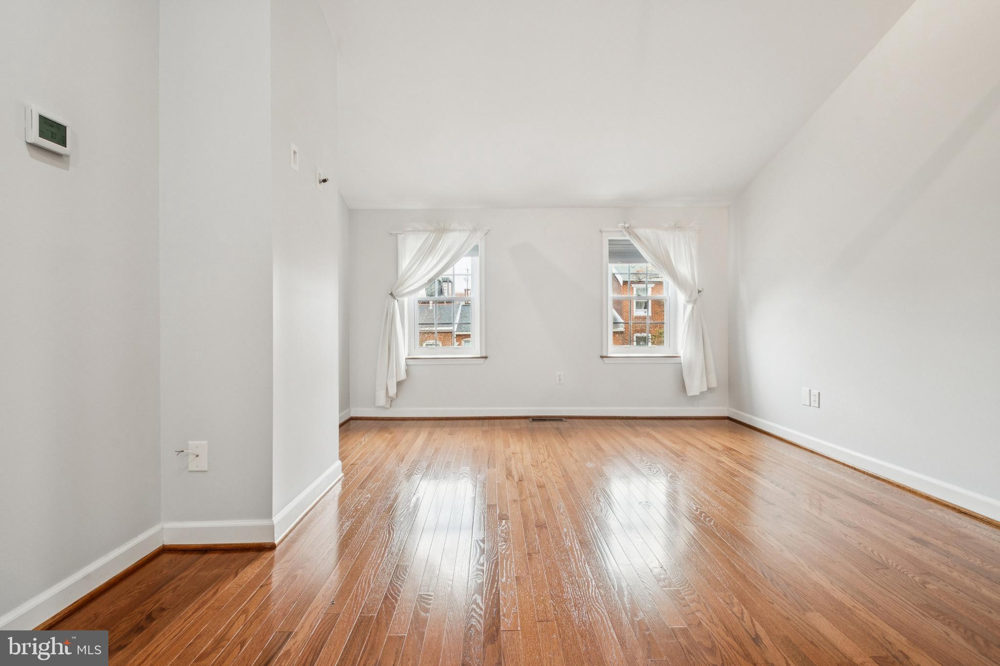 1134 Battery Avenue Baltimore, MD 21230 - Photo 19 of 30 an empty room with wooden floor white walls and windows