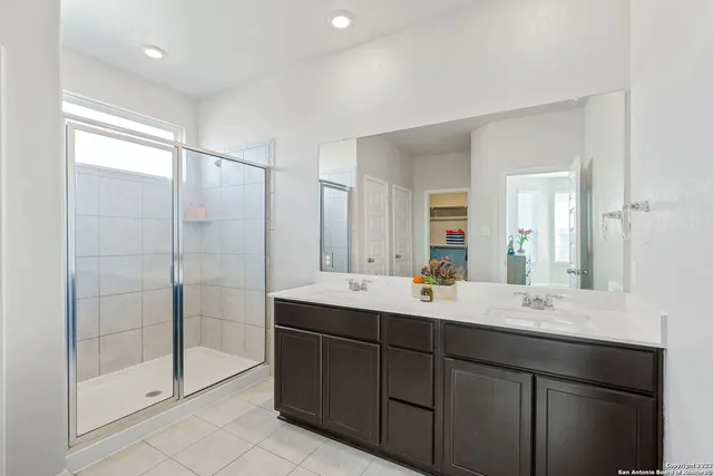a bathroom with a double vanity sink mirror and shower