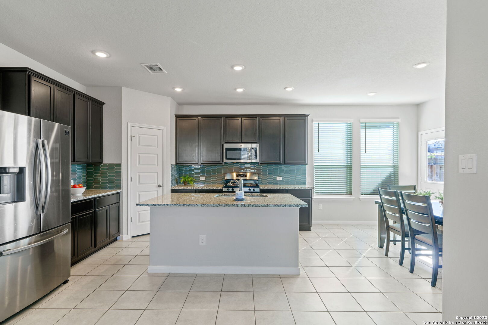 5151 Longhorn River Converse, TX 78109 - Photo 8 of 25 a kitchen with stainless steel appliances kitchen island granite countertop a refrigerator a stove a sink a dining table and chairs
