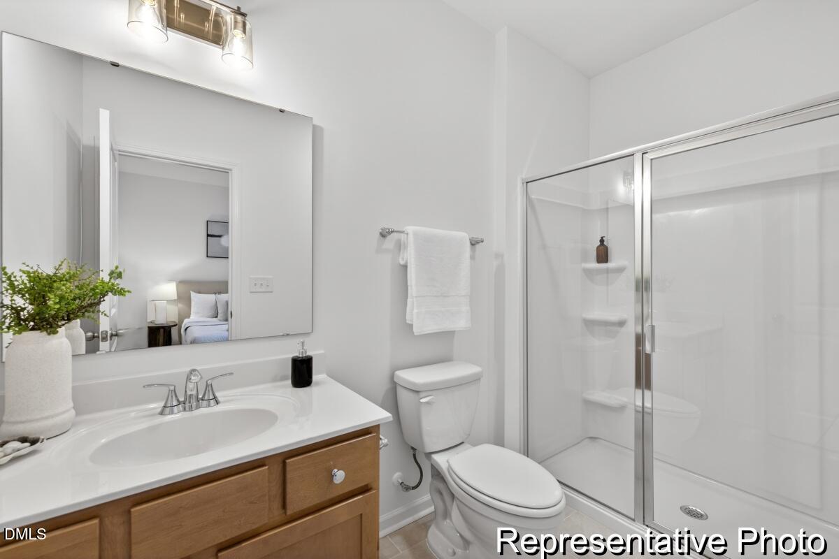 421 Plentiful Way, Unit 111 Benson, NC 27504 - Photo 23 of 27 a bathroom with a granite countertop sink toilet a mirror and shower