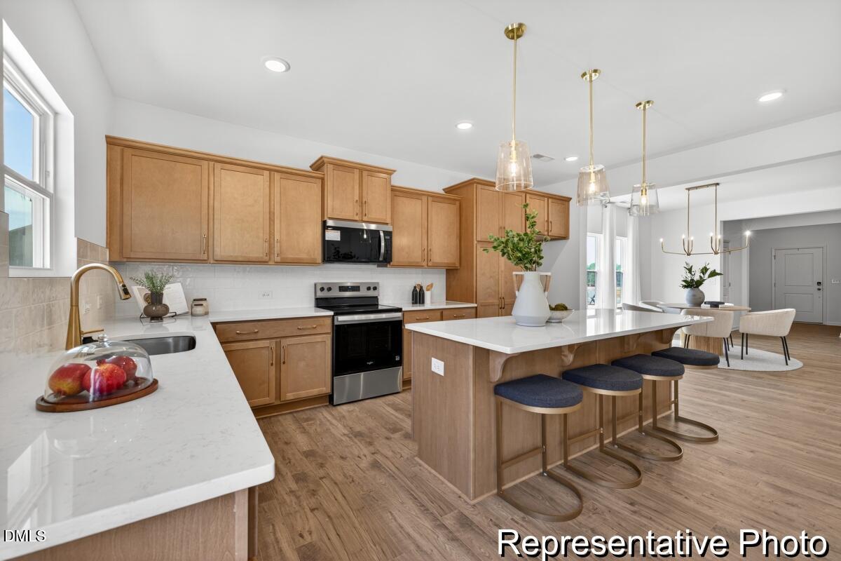 421 Plentiful Way, Unit 111 Benson, NC 27504 - Photo 3 of 27 a kitchen with a sink a stove a refrigerator and chairs