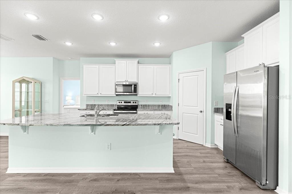 5851 Southwest 85th Place Ocala, FL 34476 - Photo 8 of 57 a large kitchen with stainless steel appliances granite countertop a refrigerator a sink a stove and white cabinets with wooden floor