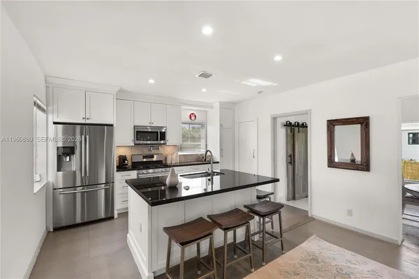 a kitchen that has a refrigerator a stove a microwave and white cabinets