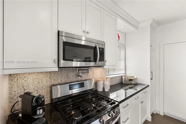 a kitchen with granite countertop a stove and a microwave