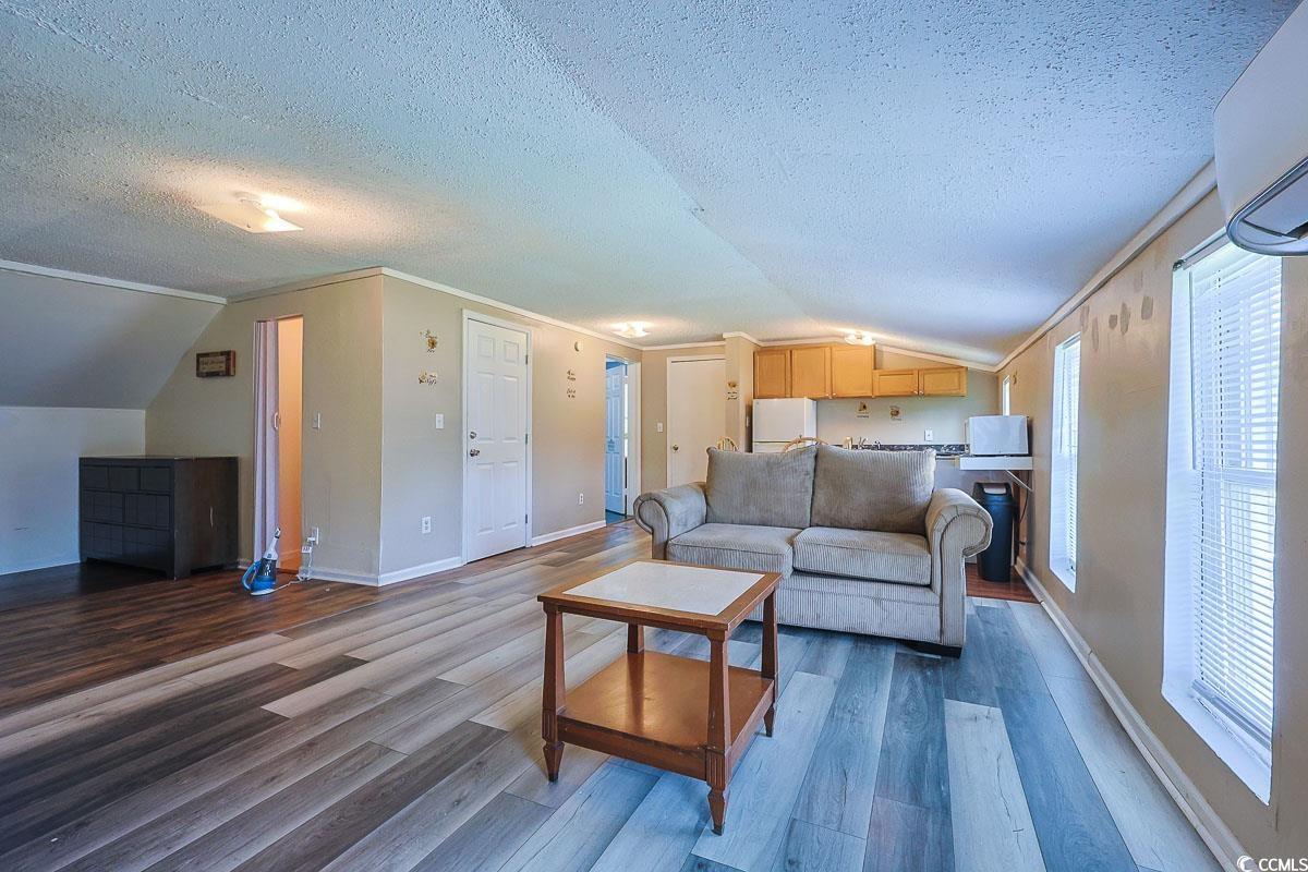 4300 Summit Trail Myrtle Beach, SC 29579 - Photo 23 of 39 Living area with vaulted ceiling, a textured ceiling, dark wood-style flooring, and an AC wall unit