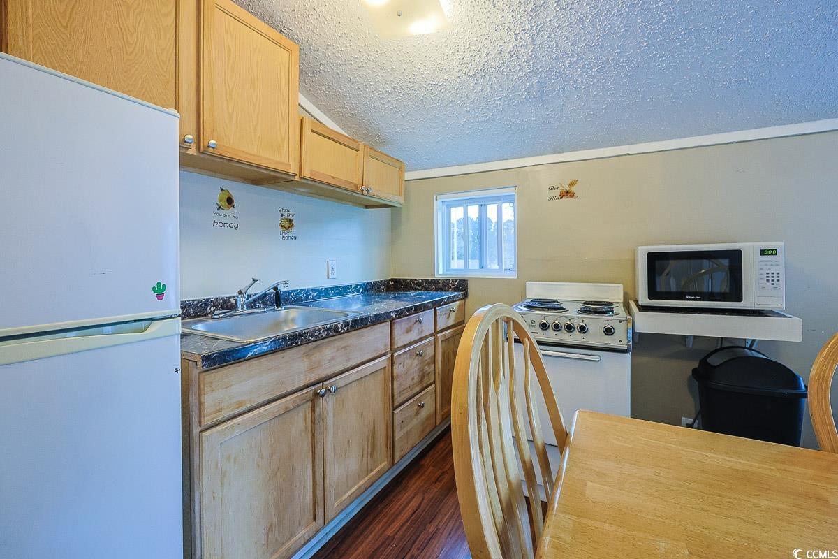 4300 Summit Trail Myrtle Beach, SC 29579 - Photo 26 of 39 Kitchen with white appliances, dark countertops, dark wood finished floors, a textured ceiling, and light brown cabinetry