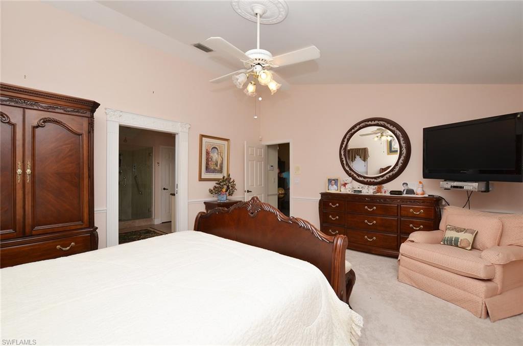 264 Henley Drive Naples, FL 34104 - Photo 14 of 25 a bedroom with a bed a mirror and a flat screen tv