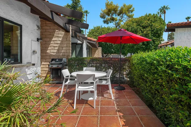 a view of a patio with table and chairs potted plants and floor to ceiling window and potted plants