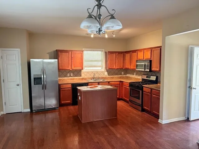 a kitchen with stainless steel appliances granite countertop a refrigerator a stove top oven a sink and dishwasher with wooden floor