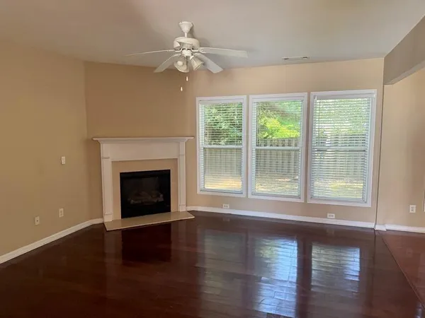 a view of an empty room with wooden floor and a fireplace