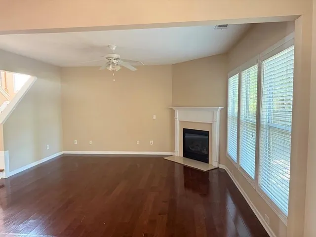 an empty room with wooden floor fireplace and windows