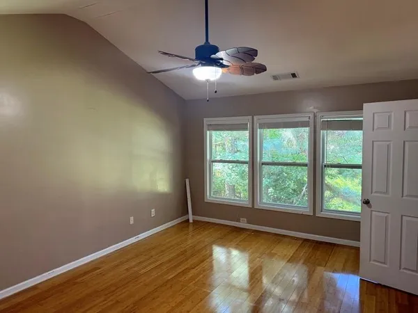 a view of an empty room with wooden floor and a window