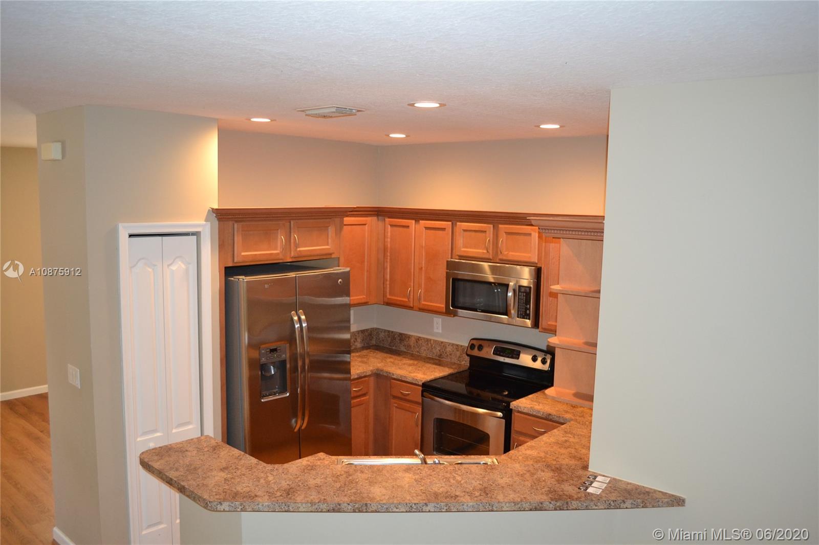 27951 Southwest 140th Avenue Homestead, FL 33032 - Photo 11 of 27 a kitchen with stainless steel appliances kitchen island granite countertop a refrigerator and a stove