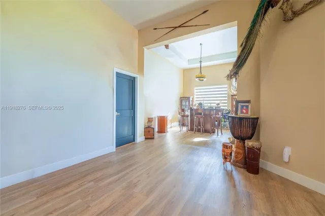 a view of a hallway to a livingroom with wooden floor and staircase