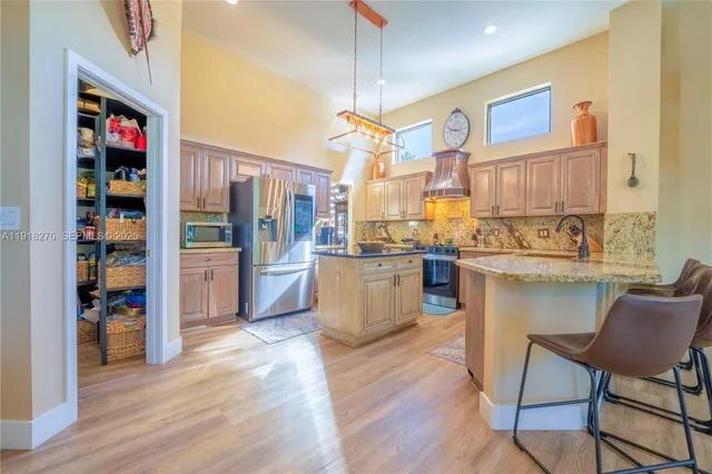 a open kitchen with stainless steel appliances granite countertop a refrigerator and a stove top oven