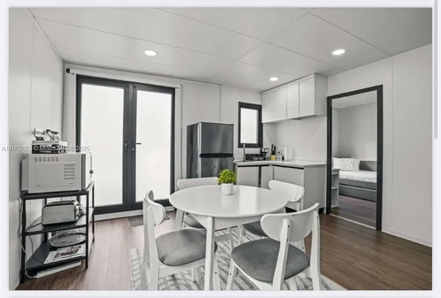 a kitchen with stainless steel appliances kitchen island granite countertop a refrigerator a stove a microwave oven with a dining table and chairs with wooden floor