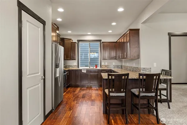 a kitchen with stainless steel appliances granite countertop dining table chairs refrigerator and microwave