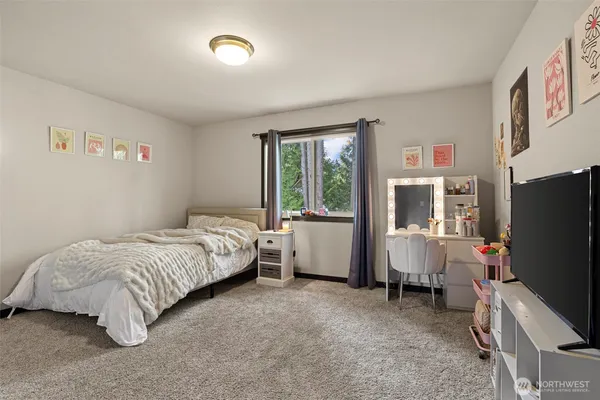 a bedroom with a bed flat screen tv and a large window