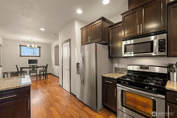a kitchen with granite countertop a refrigerator stove and microwave