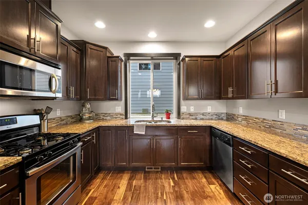 a kitchen with stainless steel appliances granite countertop wooden cabinets a stove top oven and granite countertops