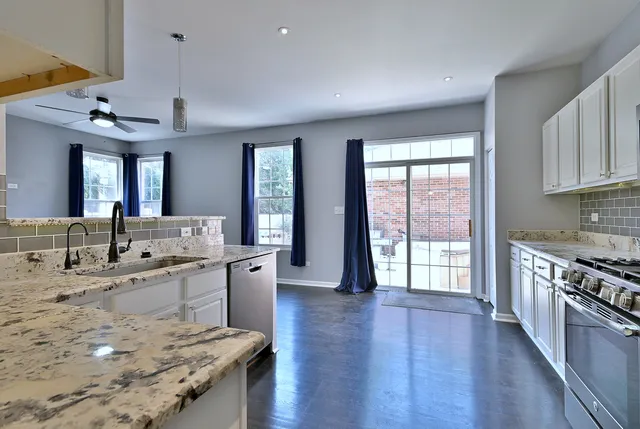 a large kitchen with stainless steel appliances granite countertop a lot of counter space and wooden floors