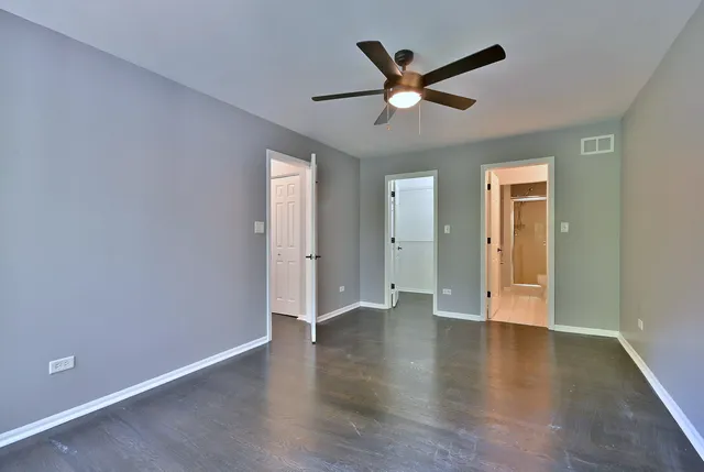 an empty room with wooden floor and a ceiling fan