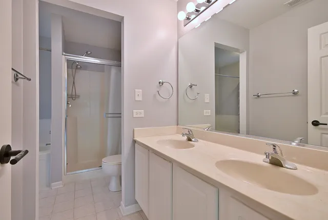 a bathroom with a sink double vanity granite toilet and shower