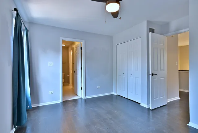 a view of an empty room with wooden floor and closet