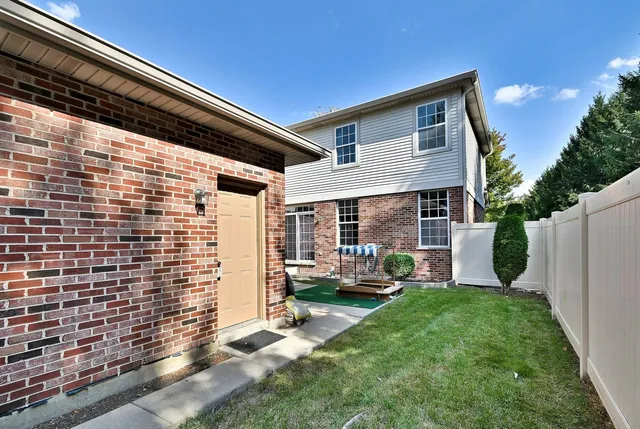 a backyard of a house with large tree and wooden fence