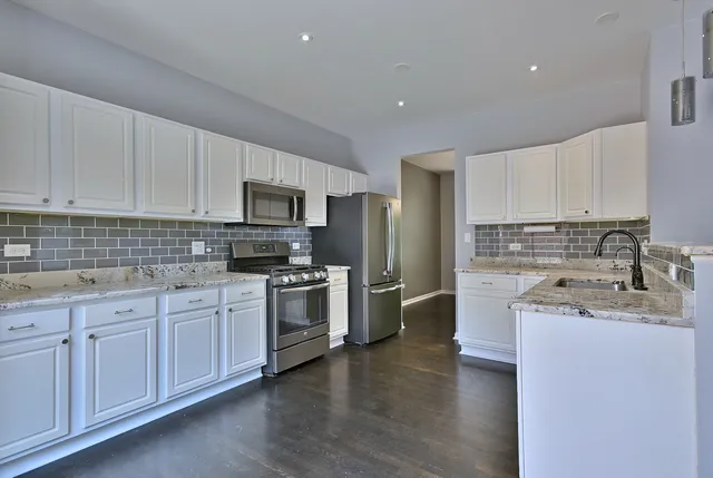 a kitchen with granite countertop a sink stainless steel appliances and cabinets
