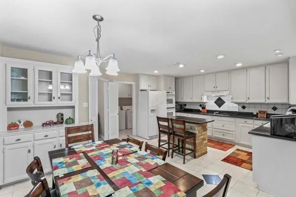 a view of a dining room and livingroom with furniture wooden floor a rug and a chandelier