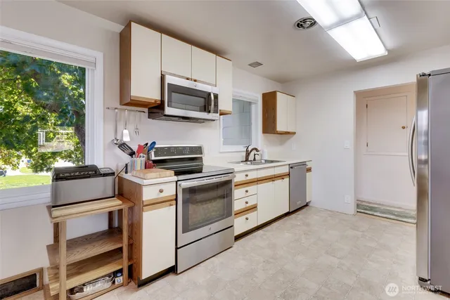 a kitchen with stainless steel appliances kitchen island granite countertop a table chairs and a refrigerator