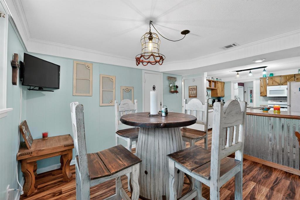 202 Senter Valley Road Irving, TX 75060 - Photo 14 of 32 Dining area featuring wood-finish flooring, light blue wall paneling, and crown molding