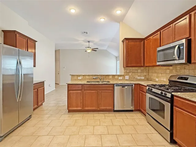 a kitchen with stainless steel appliances granite countertop a stove top oven a sink and dishwasher