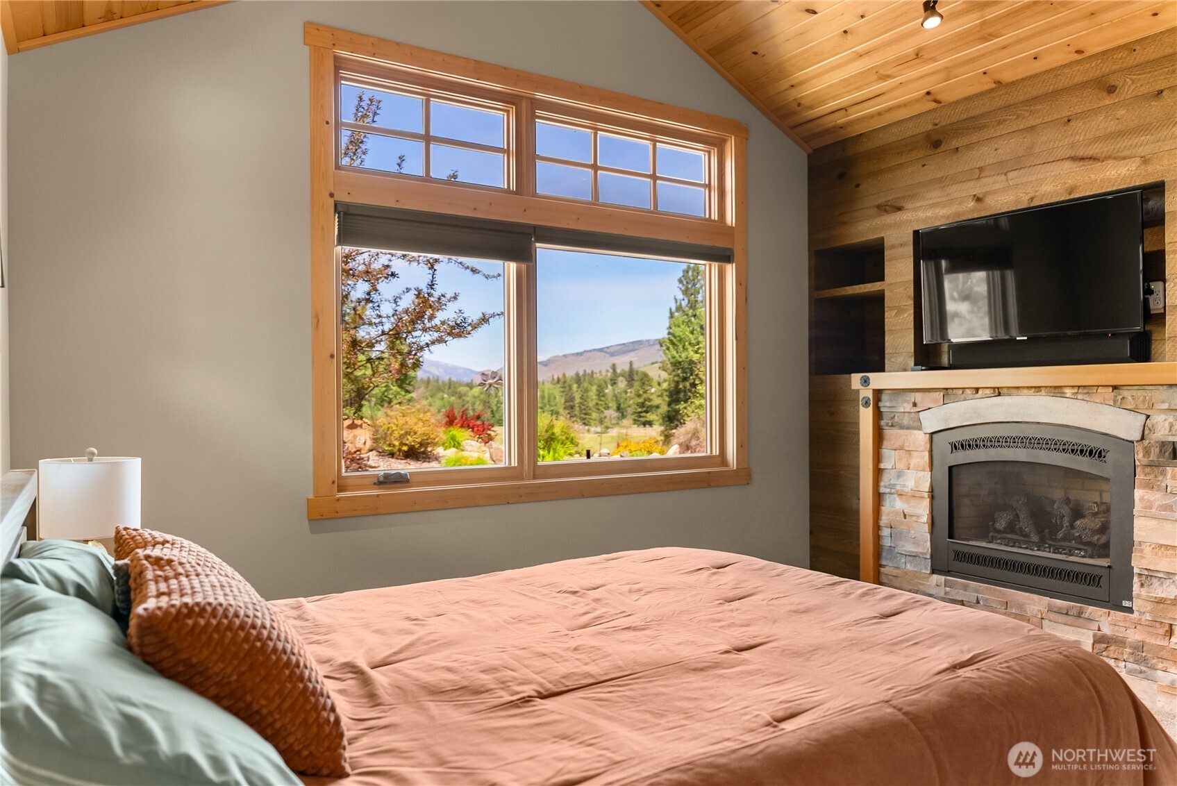 130 Sundown Road Winthrop, WA 98862 - Photo 19 of 40 a bedroom with a bed a fireplace and a window
