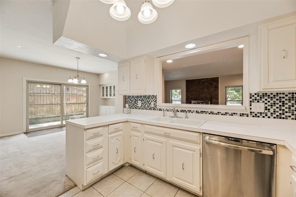 4988 Thunder Road Dallas, TX 75244 - Photo 8 of 32 Kitchen featuring white cabinetry, solid surface countertops, tile backsplash, stainless steel dishwasher, and a pass-through window