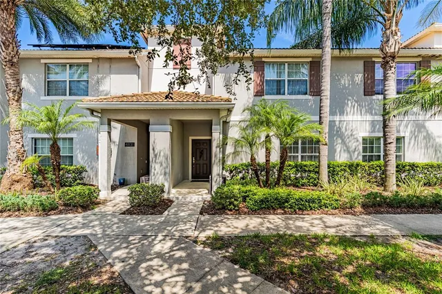 a view of a house with potted plants and a large tree