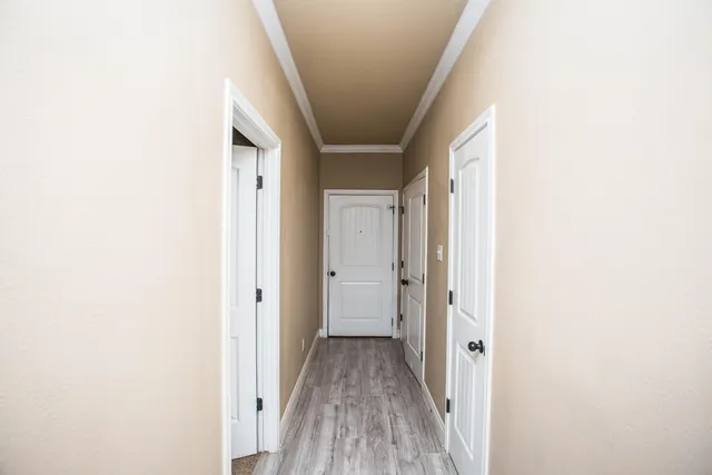 a view of a hallway with wooden floor and a bathroom