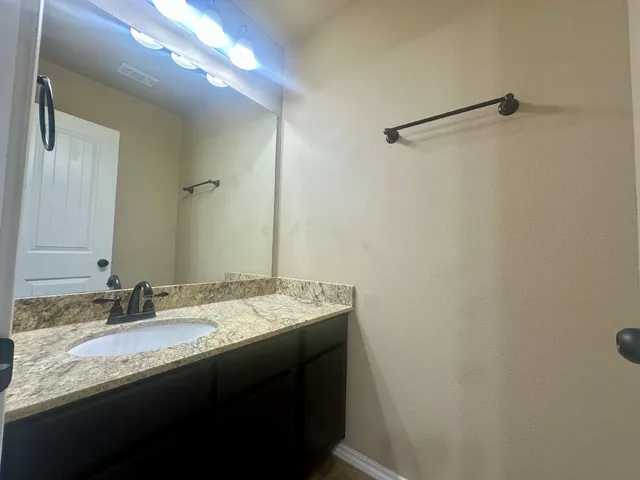 a bathroom with a granite countertop sink and a mirror