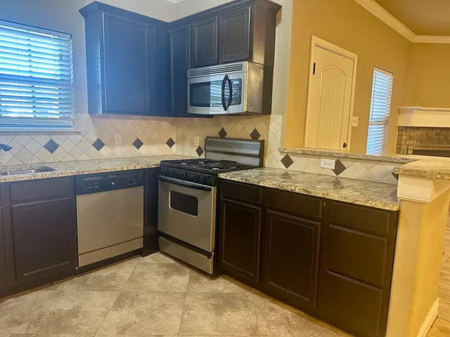 a kitchen with granite countertop a sink stove and cabinets
