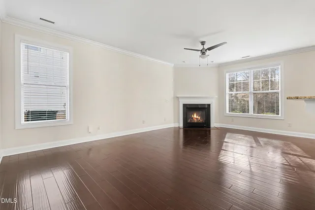 an empty room with wooden floor fireplace and windows