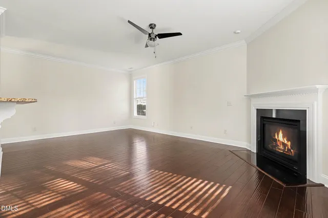 a view of an empty room with wooden floor fireplace and a window